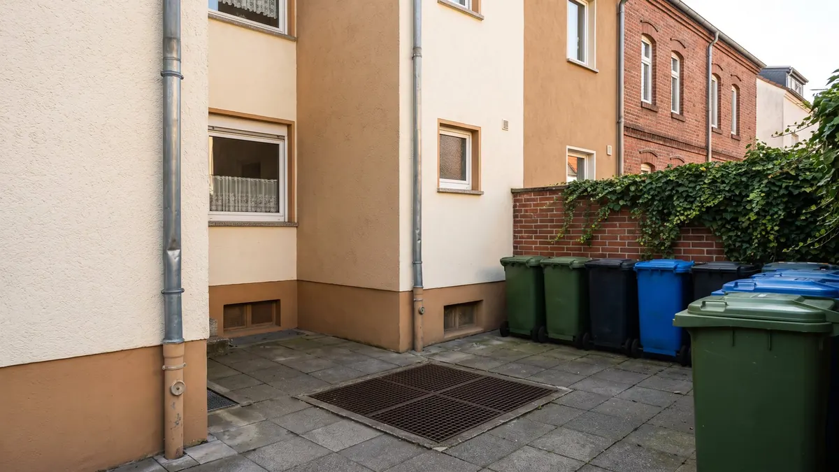 Hinterhof eines Mehrfamilienhauses mit Hofablauf und Fallrohren – Symbolbild zu Häusern und Leitungen in Selm