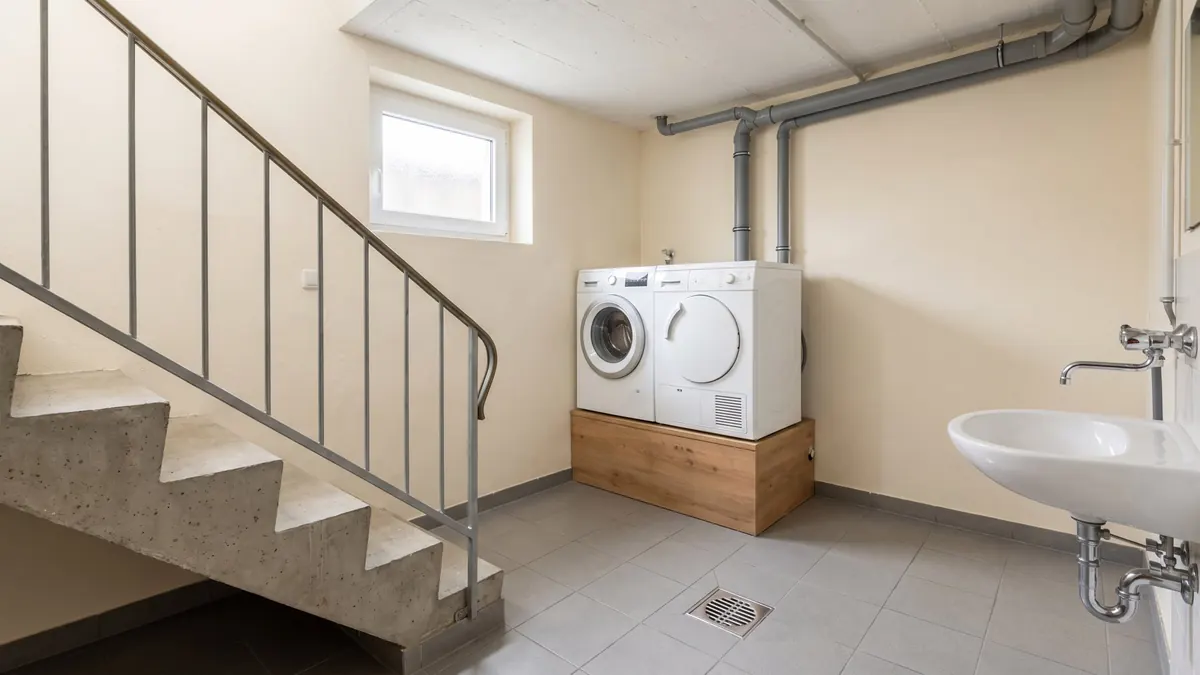 Kellertreppe hinunter in eine Waschküche mit Bodenablauf – Symbolbild zu Häusern und Leitungen in Datteln